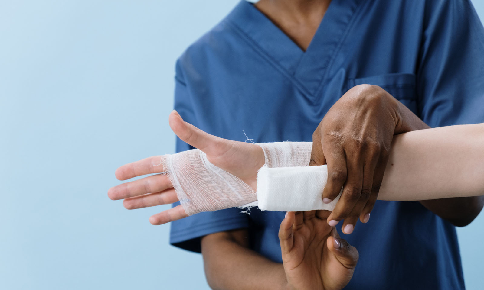 Healthcare worker in blue scrubs bandaging a wrist